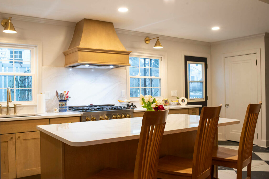 Photo of kitchen cabinets, white countertops, a oven, a sink, chairs and marble tile floors.