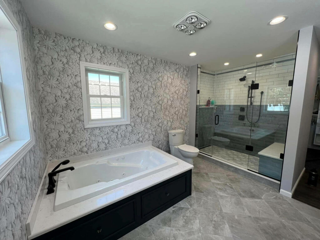 Photo of a bathroom with a tub, grey tile floors, a toilet, and a shower.