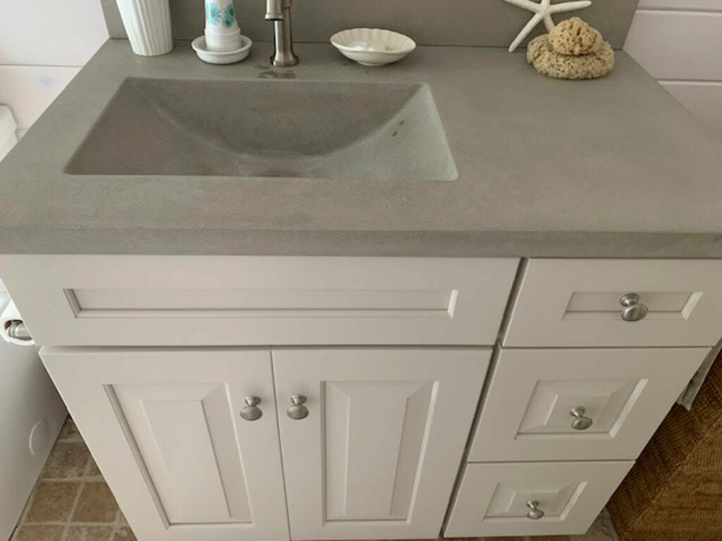 Photo of a bathroom with a white vanity and grey sink.