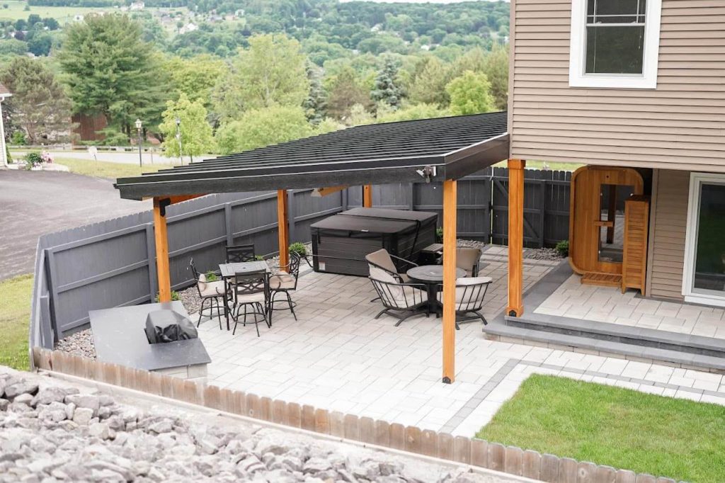 Photo of outside patio and deck with a roof, fence, chairs and tables.